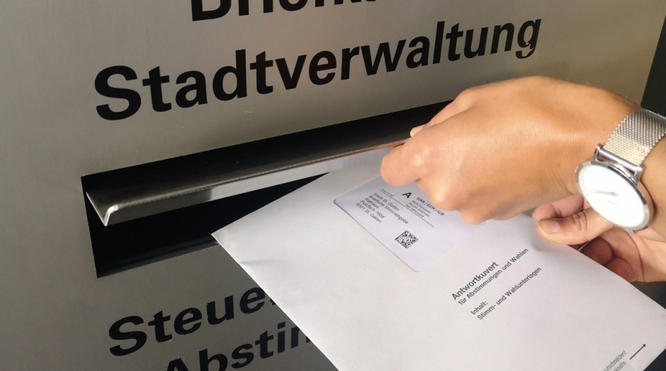 Stimmcouvert wird in Briefkasten geworfen